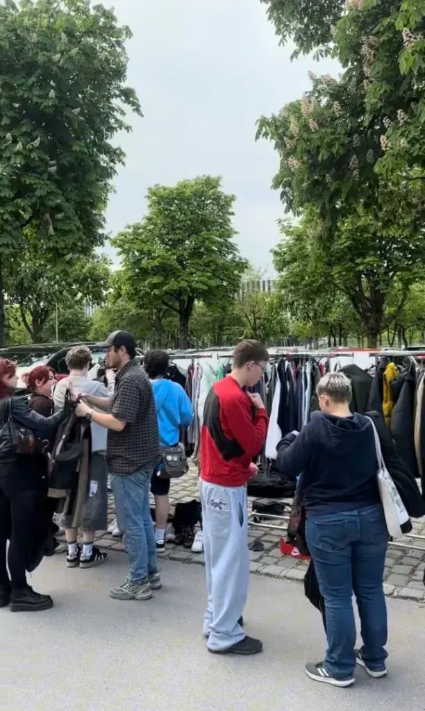 Kunden am Kleiderständer auf dem Flohmarkt